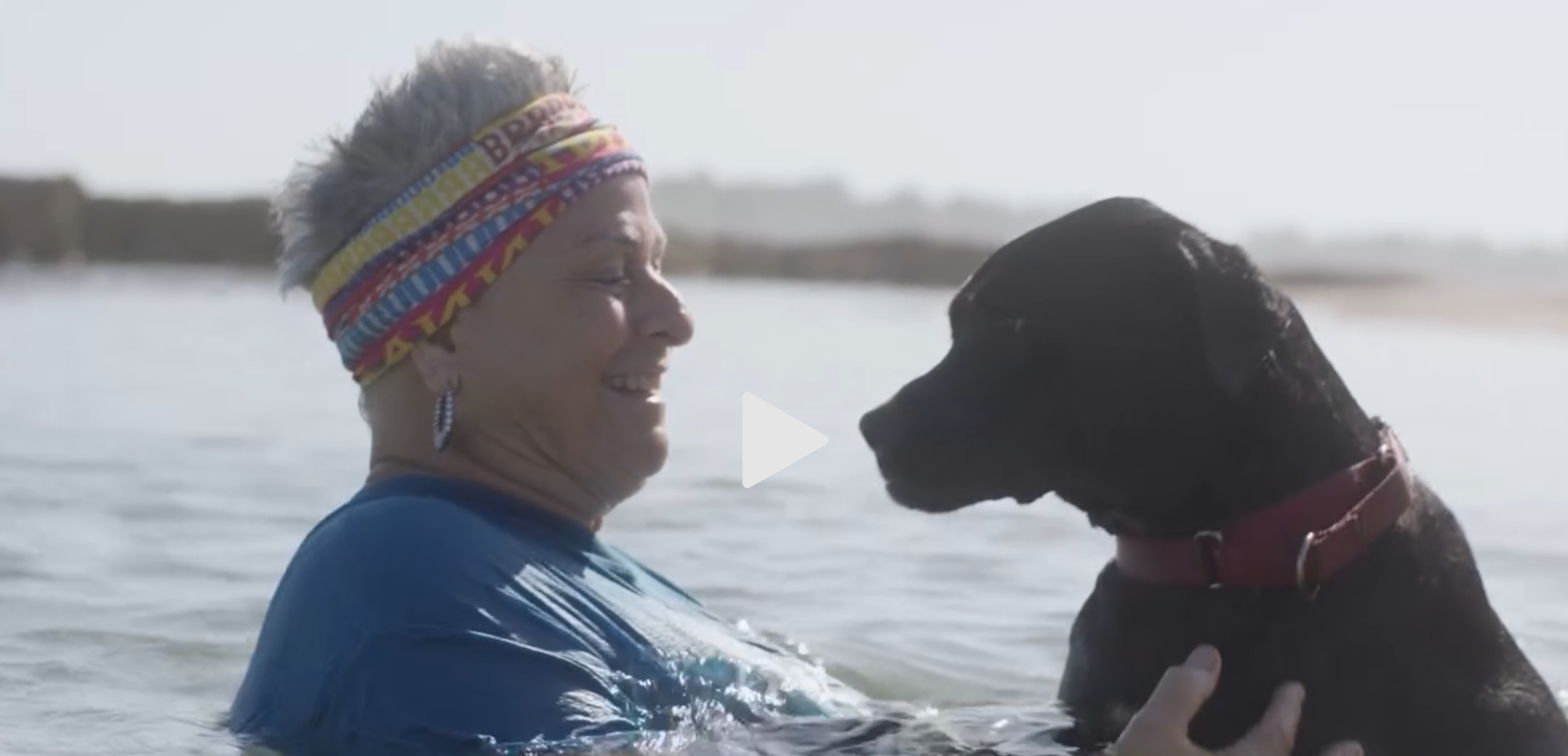 Adri Galler and a dog smiling at each other in the water