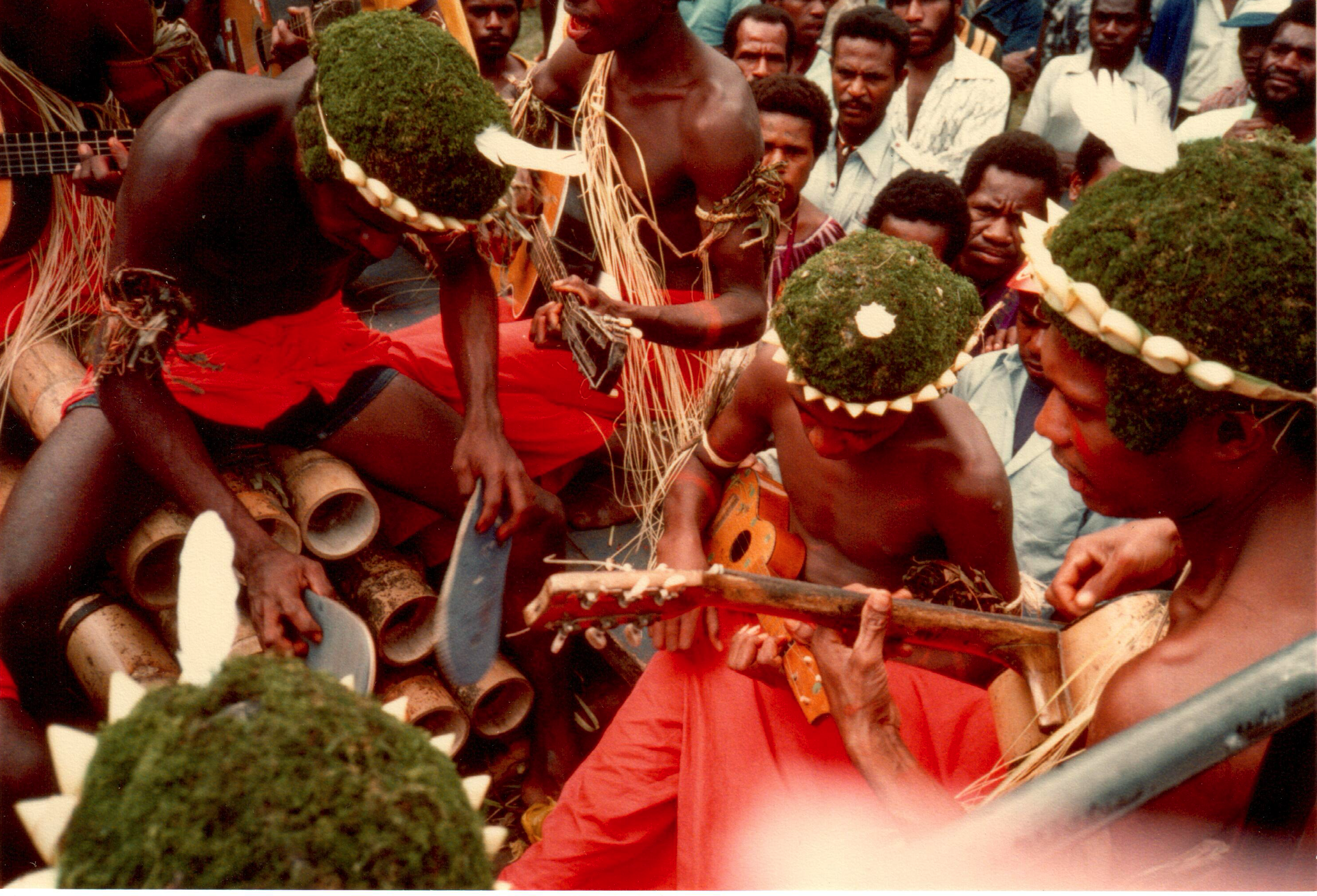 men playing music on bamboo pipes with thongs (flip-flops) at Goroka Highlands show, Papua New Guinea, 1984