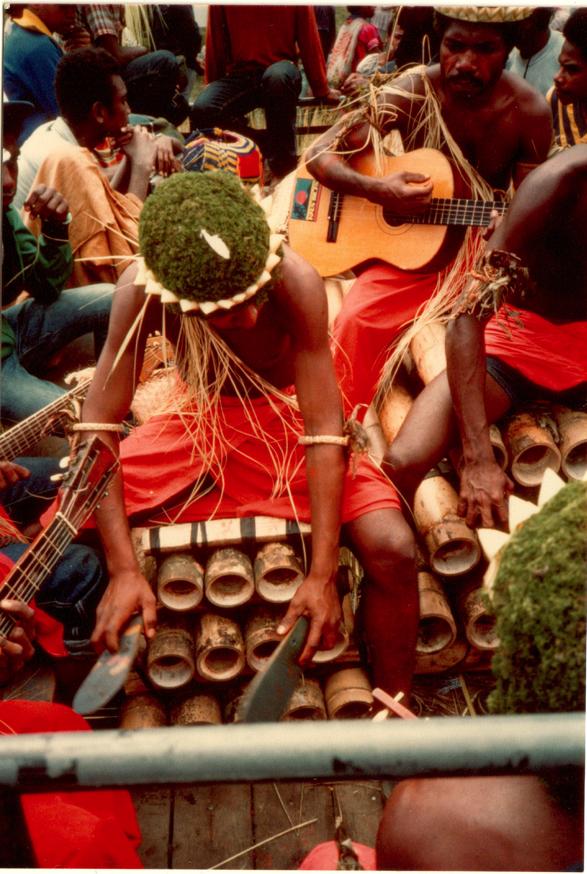 men playing music on bamboo pipes with thongs (flip-flops) at Goroka Highlands show, Papua New Guinea, 1984